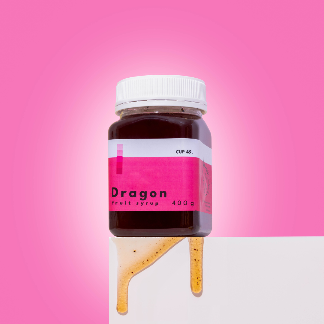 Jar of Dragon fruit syrup with a pink label on a pink background