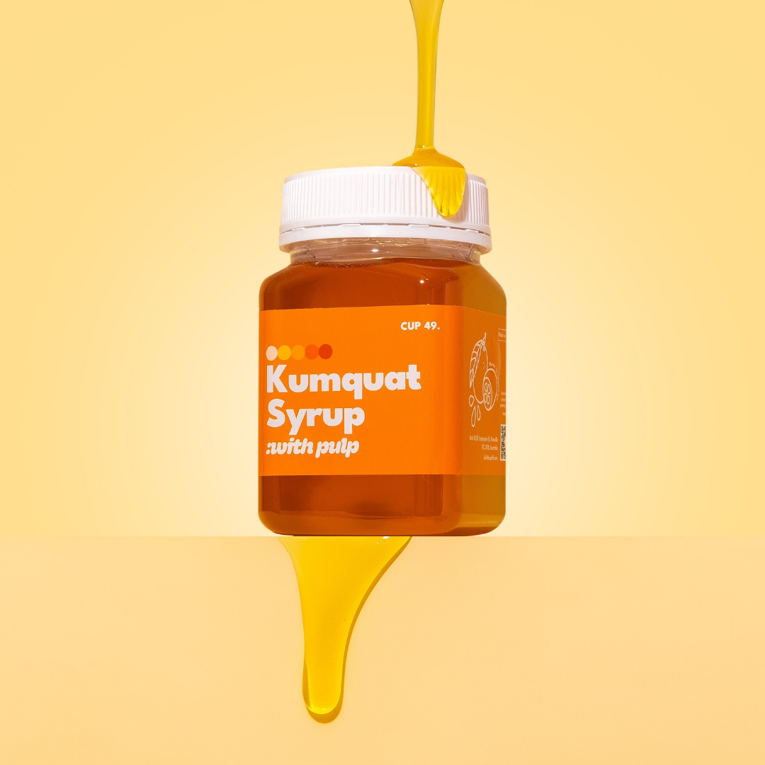 Jar of Kumquat Syrup with Pulp on a yellow background